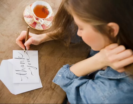 A notebook and pen next to a cup of coffee, ready for a morning 10-minute Gratitude Journaling Benefits practice.