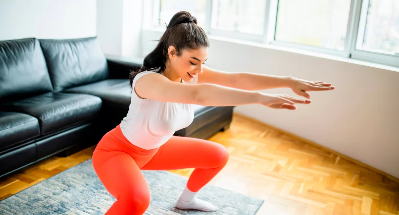 A woman performing a brisk marching in place or a side shuffle (low impact) in a living room, symbolizing a quiet No-Jump Cardio Workout.