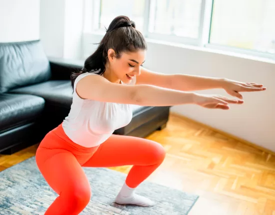 A woman performing a brisk marching in place or a side shuffle (low impact) in a living room, symbolizing a quiet No-Jump Cardio Workout.