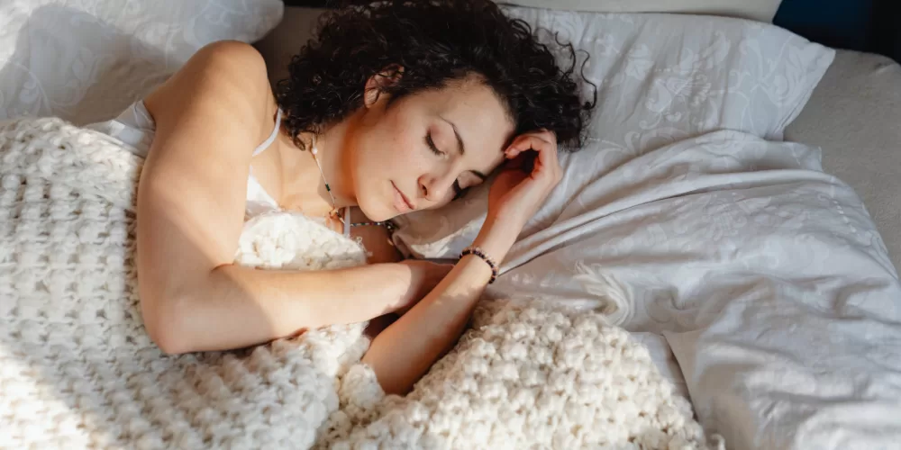 A woman meditating before bed, symbolizing the calming effect of Ayurvedic Sleep Therapy.