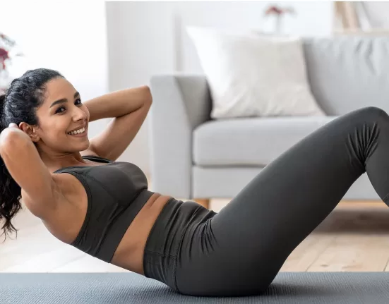 A person stretching on a couch with a remote control, humorously illustrating Fitness Hacks for Lazy People.