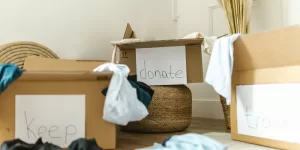 Hands sorting items into 'Keep' and 'Donate' piles, a visual of the Ways to Declutter Your Home.